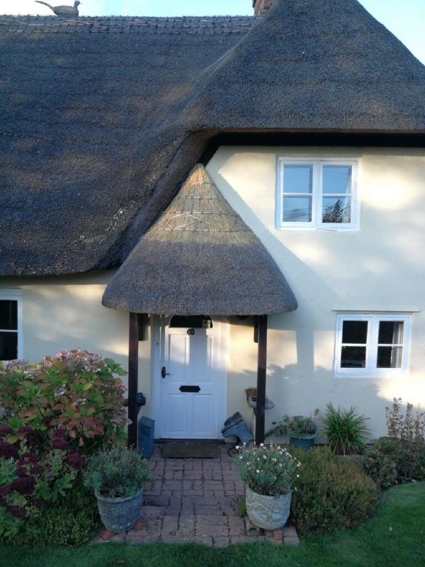 Re-thatching in progress — laying the new coat over a Wiltshire farmhouse